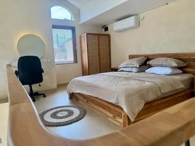 a bedroom with a bed and a chair and a window at LoftStyle Villa with nice Private Plunge Pool in Kerobokan