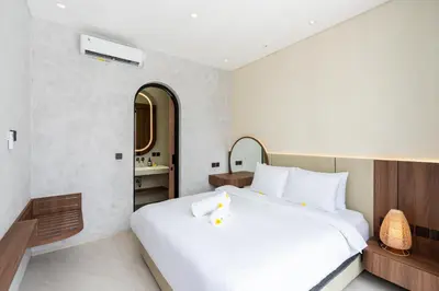 a bedroom with a large white bed and a bathroom at Casa Alden - 3BR Infinity Pool with Ricefield View in Kerobokan