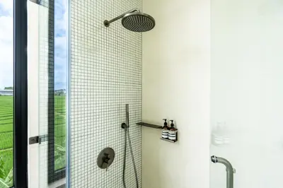 a shower with a shower head in a bathroom at Casa Alden - 3BR Infinity Pool with Ricefield View in Kerobokan