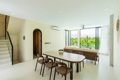a living room with a table and chairs and a couch at Casa Alden - 3BR Infinity Pool with Ricefield View in Kerobokan
