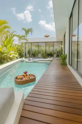 a pool with a wooden walkway leading to a house at Villa Kina - Tropical 2BR Villa with Pool and Billiard in Seminyak