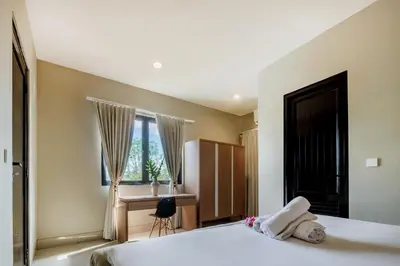 a bedroom with two beds and a desk and a window at Amelia D Art Deco Suites in Seminyak