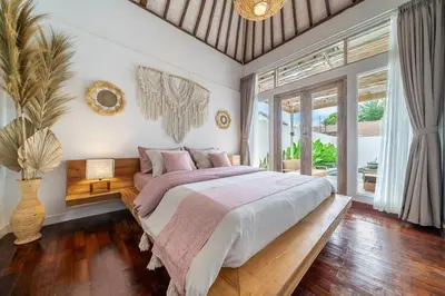 a bedroom with a large bed and a large window at Villa Arisanti in Kerobokan