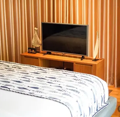 a flat screen tv sitting on a table with a bed at Dacolina House Jimbaran in Jimbaran