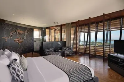 a bedroom with a large bed and a living room at Dacolina House Jimbaran in Jimbaran