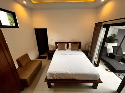 a bedroom with a bed and a chair in it at BEN & B Villa 2 in Kerobokan