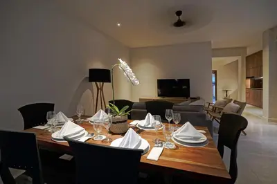 a dining room table with wine glasses and a couch at Cleo Villa Padma Legian in Seminyak