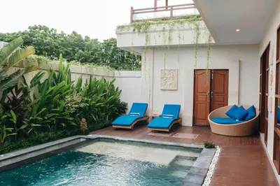 a patio with a swimming pool and blue chairs at Villa Aurikari in Legian