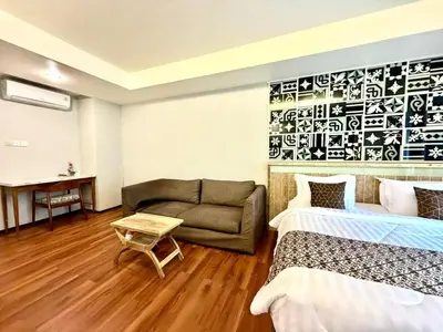 a hotel room with two beds and a couch at Dealton Hotel Sanur in Sanur