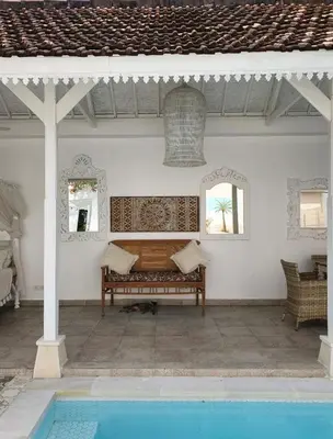 a patio with a bench next to a swimming pool at Gypsy Boutique Villa in Seminyak