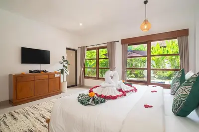 a bedroom with a large white bed with flowers on it at Villa WENDY Mertanadi in Seminyak