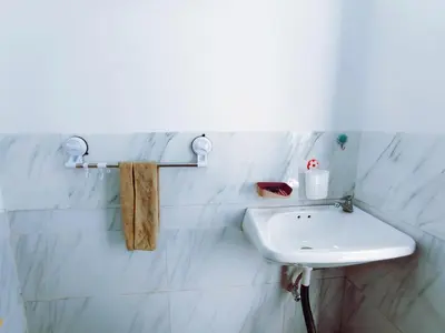 a white sink in a white tiled bathroom at Joy Private Pool Villa in Kuta