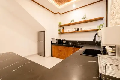 a kitchen with a black counter top and a refrigerator at Green Mutiara Jimbaran in Jimbaran