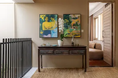 a living room with a wooden table and paintings on the wall at Villa Arta - A Calm, Tropical Villa in Umalas in Canggu