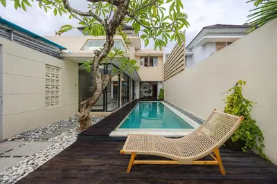 a villa with a swimming pool and a chair at Villa Arta - A Calm, Tropical Villa in Umalas in Canggu