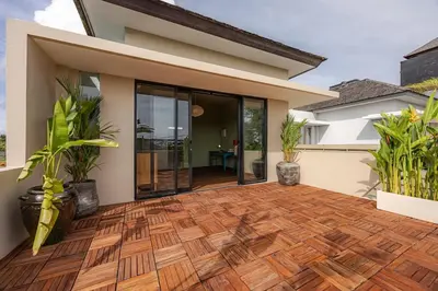 a house with a wooden floor and glass doors at Villa Arta - A Calm, Tropical Villa in Umalas in Canggu
