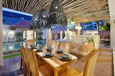 a dining room with a wooden table and chairs at 5BR Luxury Berawa Canggu with Butler in Canggu