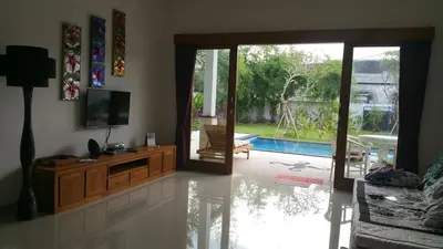 a living room with a television and a sliding glass door at Elegant oasis between Canggu and Seminyak in Kerobokan