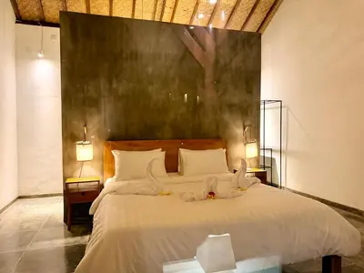 a bedroom with a large bed with white sheets and candles at Nauu Villa Umalas in Kerobokan