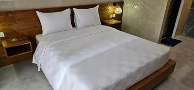 a bedroom with a large white bed with two tables at Jepun segara homestay in Ngurah Rai International Airport