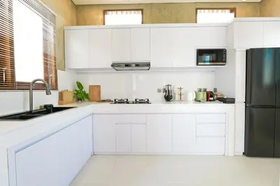 a kitchen with white cabinets and a black refrigerator at 1BR Japanese Inspired Bali Villa in Kerobokan in Kerobokan