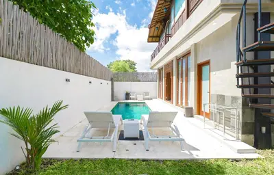 a pool with two chairs and a table next to a house at 1BR Japanese Inspired Bali Villa in Kerobokan in Kerobokan