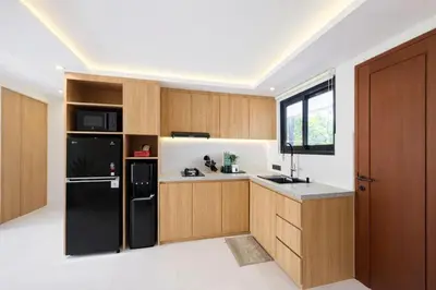 a kitchen with wooden cabinets and a black refrigerator at Private Pool Villa Near Uluwatu in Jimbaran