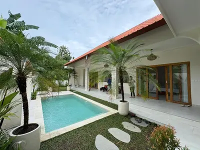 a house with a swimming pool and palm trees at Villa Makna Canggu in Canggu