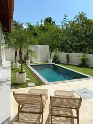a swimming pool with two chairs and a table at Villa Makna Canggu in Canggu