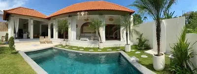 a villa with a swimming pool in front of a house at Villa Makna Canggu in Canggu