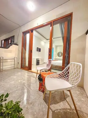 a room with two white chairs and a bed at Ratu Guest House in Mantaak