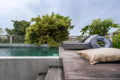 a pool with a couch on a wooden deck at Duur Apartment by Betterplace in Seminyak