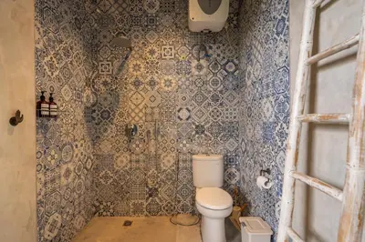 a bathroom with a toilet and blue tiles at Duur Apartment by Betterplace in Seminyak