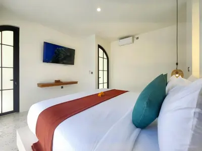 a bedroom with a large white bed with blue pillows at Villa Emilia Canggu by Nagisa Bali in Canggu