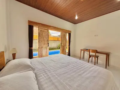 a bedroom with a bed and a desk and a window at Tanhana Seminyak in Kerobokan