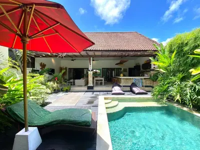 a red umbrella sitting next to a swimming pool at Superb Location! Modern 2BR Seminyak Oasis with Pool & Garden in Seminyak