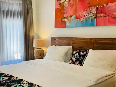 a bedroom with a bed and a painting on the wall at Superb Location! Modern 2BR Seminyak Oasis with Pool & Garden in Seminyak