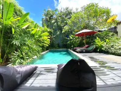 a swimming pool with an umbrella and two chairs at Superb Location! Modern 2BR Seminyak Oasis with Pool & Garden in Seminyak