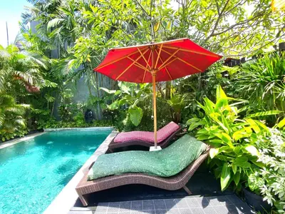 a red umbrella and chairs next to a swimming pool at Superb Location! Modern 2BR Seminyak Oasis with Pool & Garden in Seminyak