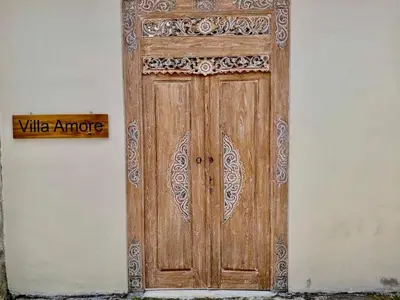 an old wooden door on the side of a building at Authentic Balinese Riverside Villa in Kerobokan