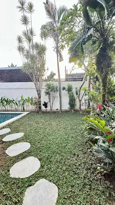 a garden with rocks and trees and a swimming pool at Authentic Balinese Riverside Villa in Kerobokan