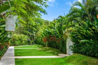a garden with green grass and trees and a pathway at Yahira Stunning Garden 5 BR Private Pool Villa in Canggu