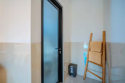 a glass door in a room with a chair at Wana Kubu Suite and Dormitory in Ngurah Rai International Airport