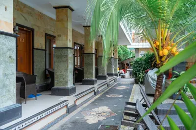 a building with a courtyard with palm trees and chairs at Wana Kubu Suite and Dormitory in Ngurah Rai International Airport