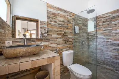 a bathroom with a stone sink and a toilet at Legian Beach Villa - 3-room open villa, private pool, near the beach, Netflix in Legian