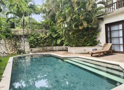 a swimming pool with a bench next to a house at Calladi Villa in Seminyak