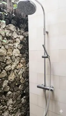 a shower in a bathroom with a stone wall at Calladi Villa in Seminyak