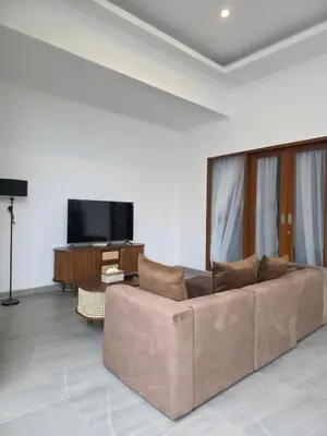 a living room with a brown couch and a flat screen tv at Le Calme Villa Brand New 2 BR Private Villa near Seminyak in Kerobokan