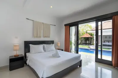 a bedroom with a large bed and a pool at Homy 3 Bedrooms Villas in Canggu Umalas in Kerobokan