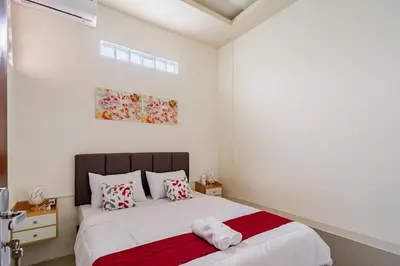 a white bedroom with a bed with a red blanket at Dbelid Royal House - Private 5BR Villa in Jimbaran in Jimbaran